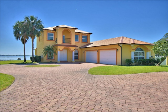 mediterranean / spanish-style home with stucco siding, decorative driveway, and a water view