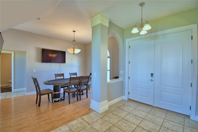 foyer entrance featuring a notable chandelier, light tile patterned floors, arched walkways, and baseboards