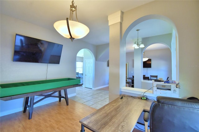 interior space with an inviting chandelier, tile patterned floors, baseboards, and arched walkways