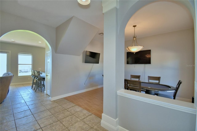 interior space with tile patterned floors, arched walkways, and baseboards