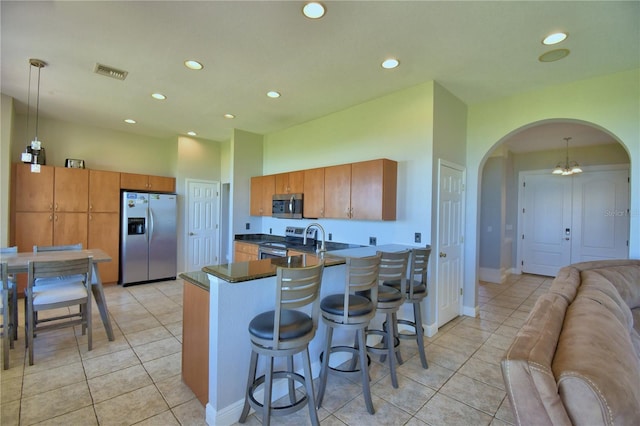 kitchen with visible vents, a breakfast bar, a peninsula, arched walkways, and appliances with stainless steel finishes