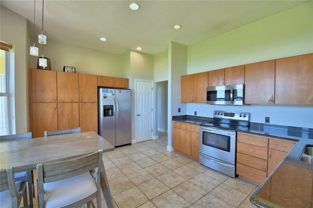 kitchen with pendant lighting, light tile patterned floors, brown cabinetry, and stainless steel appliances