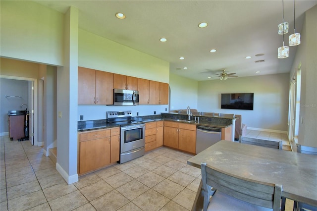 kitchen with a sink, recessed lighting, stainless steel appliances, a peninsula, and light tile patterned flooring