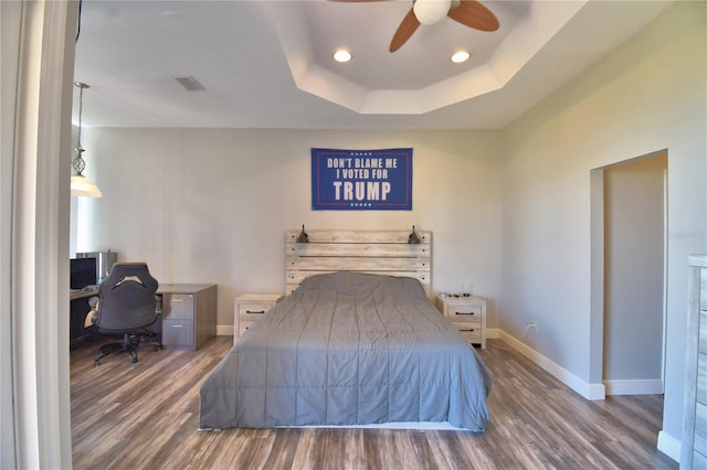 bedroom featuring visible vents, baseboards, a raised ceiling, and wood finished floors