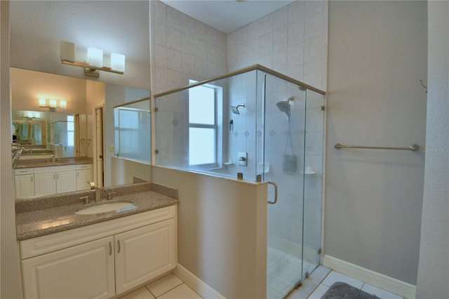 bathroom with vanity, tile patterned floors, baseboards, and a shower stall