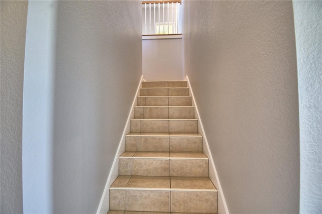 stairs featuring tile patterned flooring, baseboards, and a textured wall