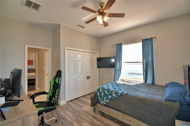 bedroom featuring ceiling fan, visible vents, a closet, and wood finished floors