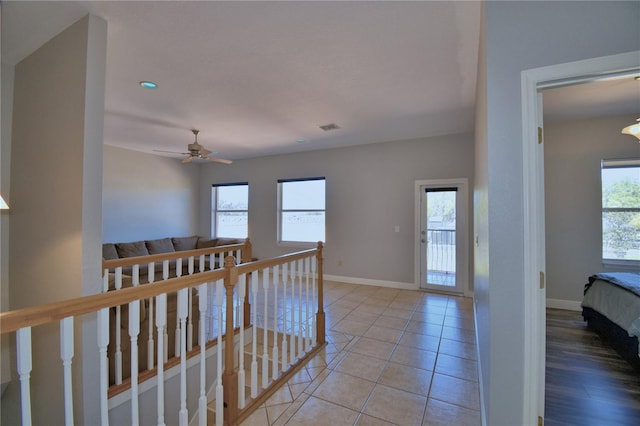 hall with plenty of natural light, an upstairs landing, visible vents, and baseboards