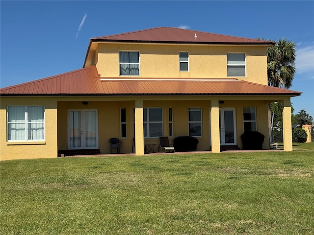 back of house with stucco siding, french doors, and a lawn