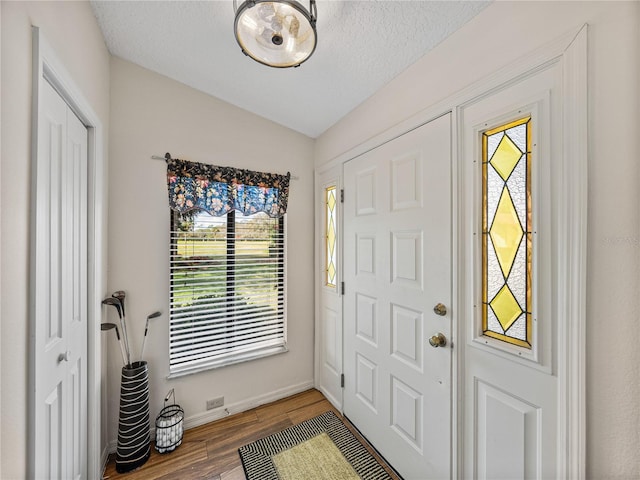 foyer entrance with lofted ceiling, hardwood / wood-style flooring, and a textured ceiling