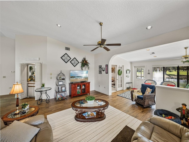 living room featuring wood-type flooring, a textured ceiling, vaulted ceiling, and ceiling fan