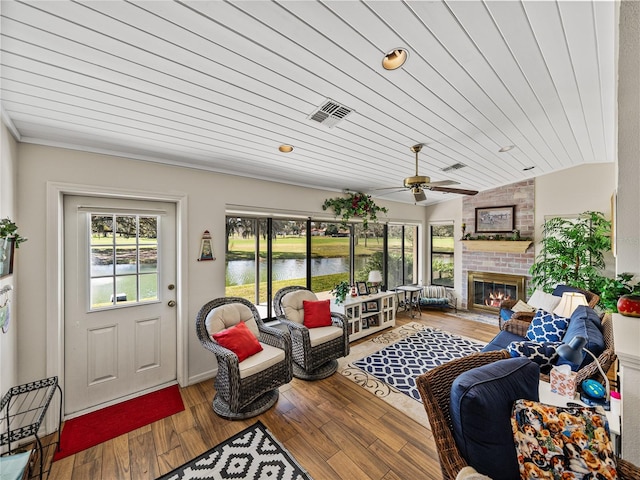 living room featuring hardwood / wood-style flooring, a water view, a brick fireplace, vaulted ceiling, and wooden ceiling