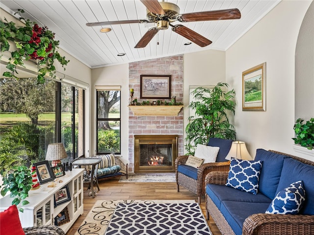 living room featuring vaulted ceiling, a brick fireplace, light hardwood / wood-style flooring, wooden ceiling, and ornamental molding