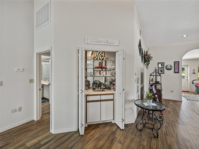 corridor with dark hardwood / wood-style floors, a textured ceiling, and a high ceiling