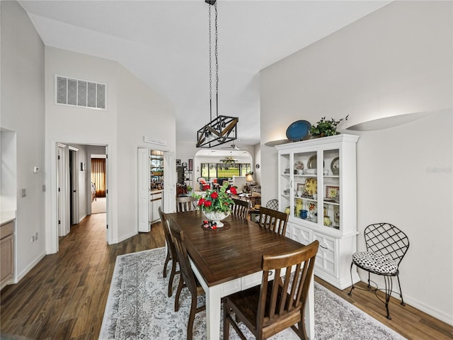 dining space featuring dark wood-type flooring and high vaulted ceiling