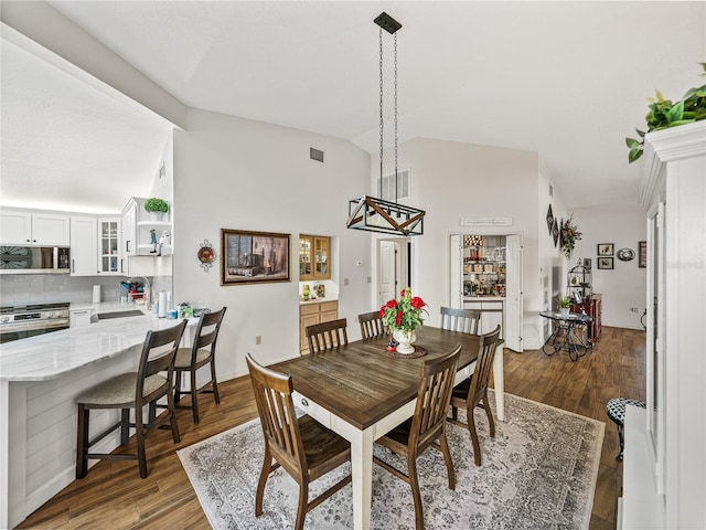 dining room featuring dark wood-type flooring and vaulted ceiling