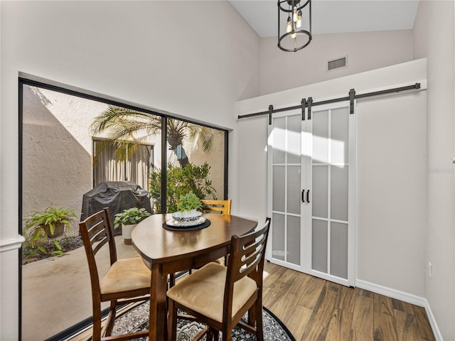 dining room featuring lofted ceiling, wood-type flooring, and a barn door