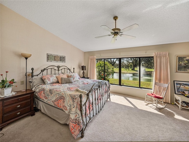 carpeted bedroom with lofted ceiling, ceiling fan, a textured ceiling, and a water view