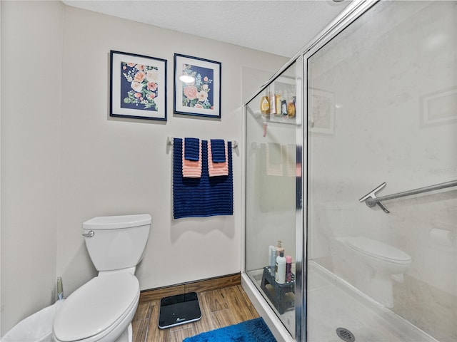 bathroom featuring walk in shower, toilet, hardwood / wood-style floors, and a textured ceiling