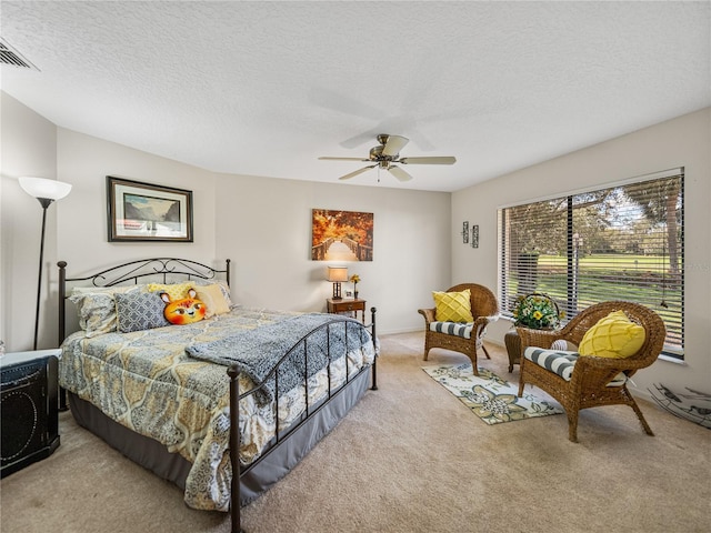 bedroom with ceiling fan, light carpet, and a textured ceiling