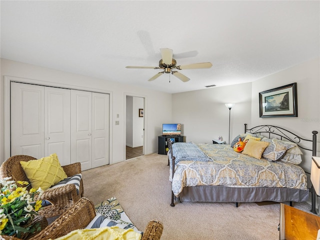 carpeted bedroom with ceiling fan and a closet