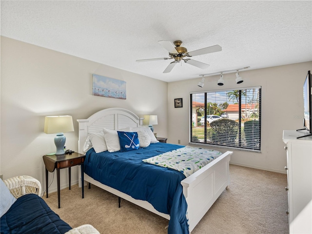 bedroom featuring ceiling fan, light colored carpet, track lighting, and a textured ceiling