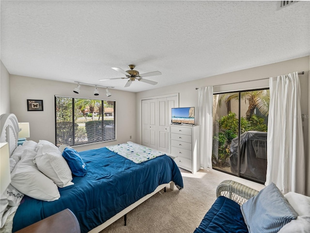 carpeted bedroom featuring access to exterior, a textured ceiling, a closet, and ceiling fan