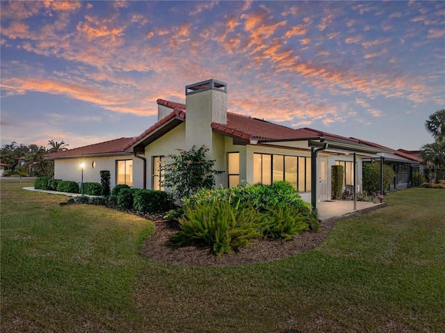 back house at dusk with a yard and a patio area