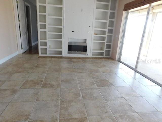 unfurnished living room with light tile patterned floors and built in features