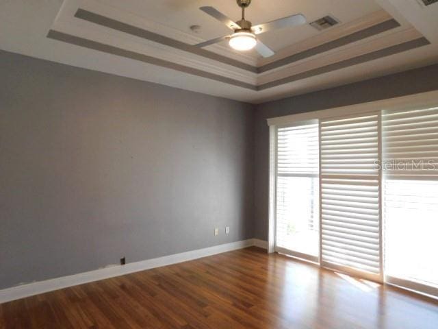 spare room featuring hardwood / wood-style floors, crown molding, a raised ceiling, and ceiling fan