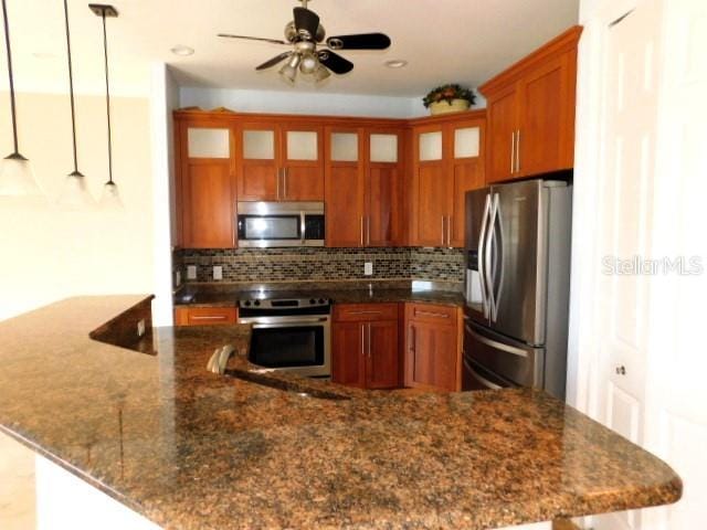 kitchen with pendant lighting, ceiling fan, appliances with stainless steel finishes, and decorative backsplash