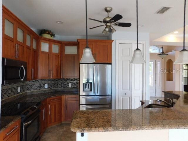 kitchen with tasteful backsplash, appliances with stainless steel finishes, hanging light fixtures, and ceiling fan