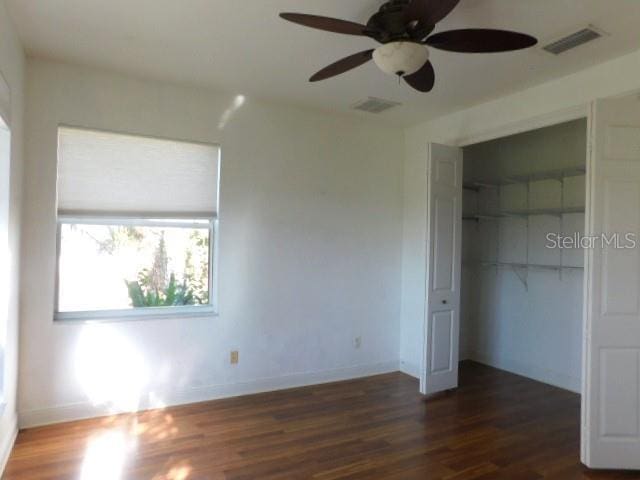 unfurnished bedroom featuring ceiling fan, dark hardwood / wood-style flooring, and a closet