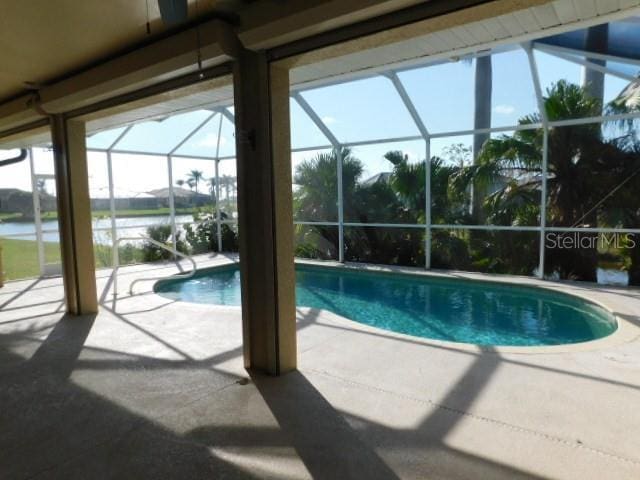 view of pool featuring a water view, a patio area, and a lanai