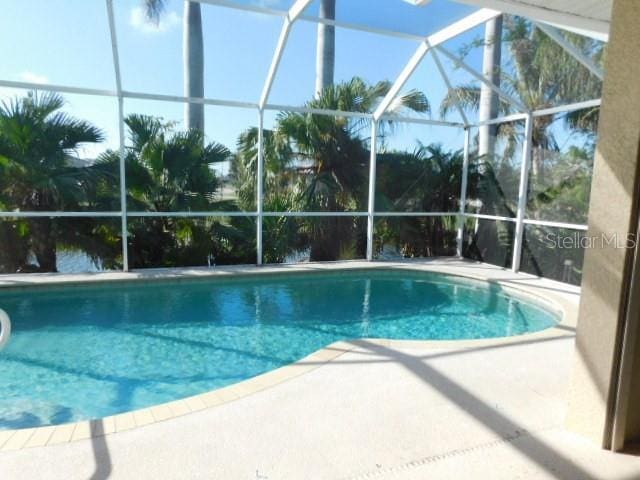 view of swimming pool featuring a patio area and glass enclosure