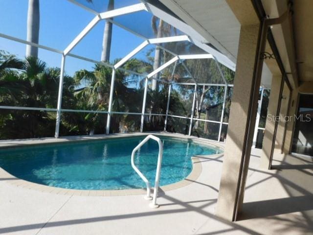 view of swimming pool featuring a patio and glass enclosure