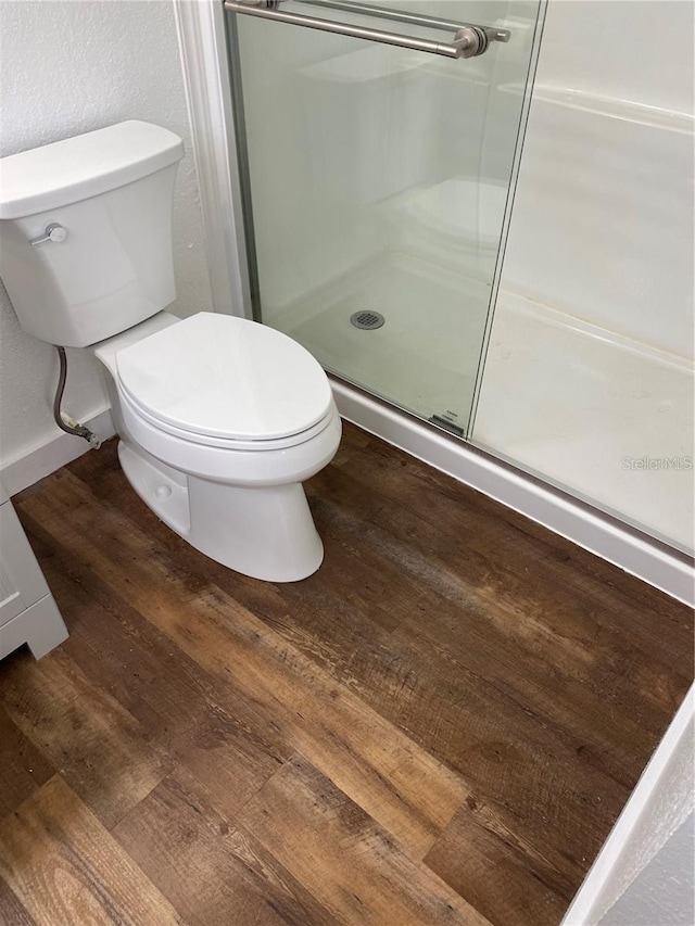 bathroom featuring a shower with door, wood-type flooring, and toilet