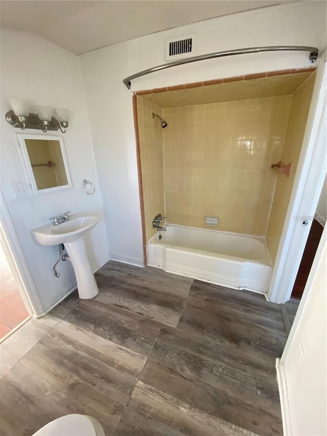 bathroom featuring hardwood / wood-style floors, toilet, and tiled shower / bath