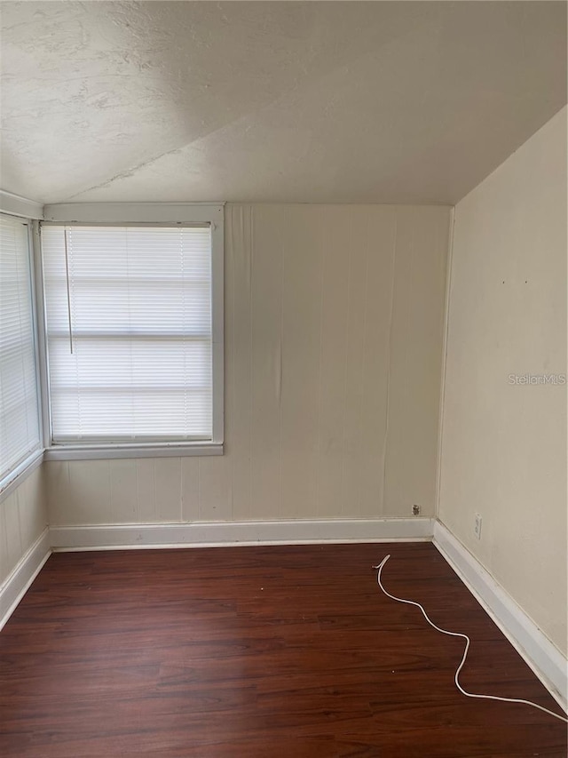 unfurnished room with dark hardwood / wood-style floors and vaulted ceiling