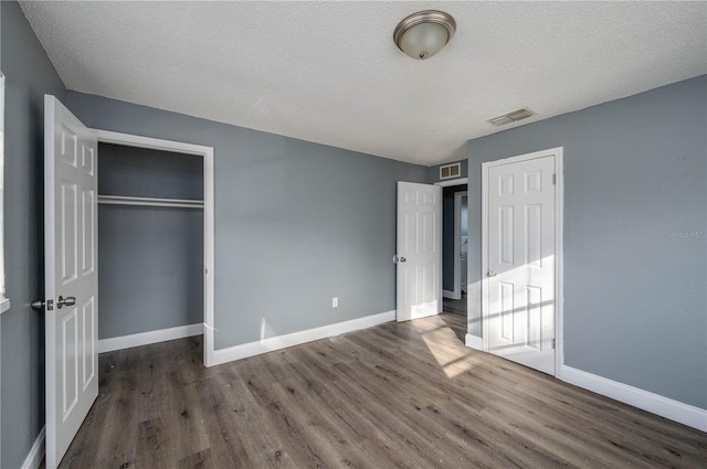 unfurnished bedroom featuring visible vents, baseboards, and wood finished floors