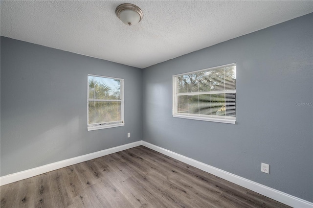 empty room with hardwood / wood-style floors and a textured ceiling