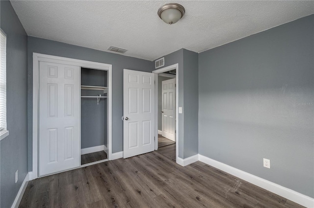 unfurnished bedroom featuring a closet, visible vents, dark wood-type flooring, and baseboards