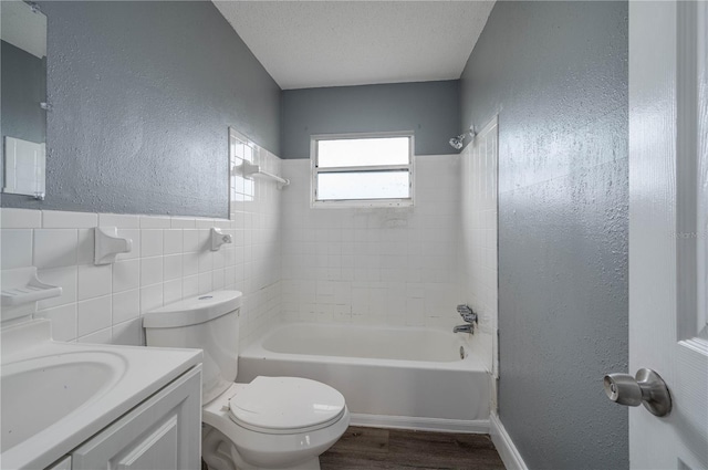 bathroom with toilet, a textured ceiling, tile walls, bathing tub / shower combination, and a textured wall