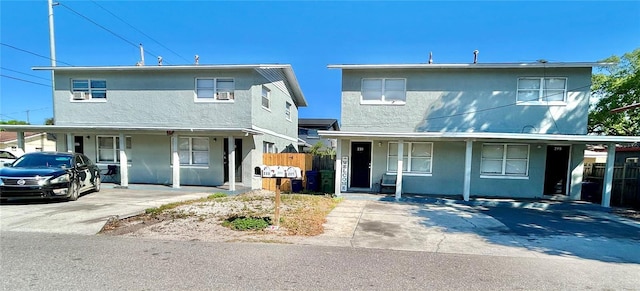 view of front of property featuring stucco siding, covered porch, and fence