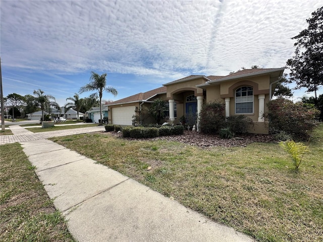 ranch-style home featuring concrete driveway, a front lawn, an attached garage, and stucco siding