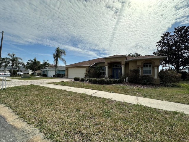 single story home with driveway, an attached garage, a front yard, and stucco siding