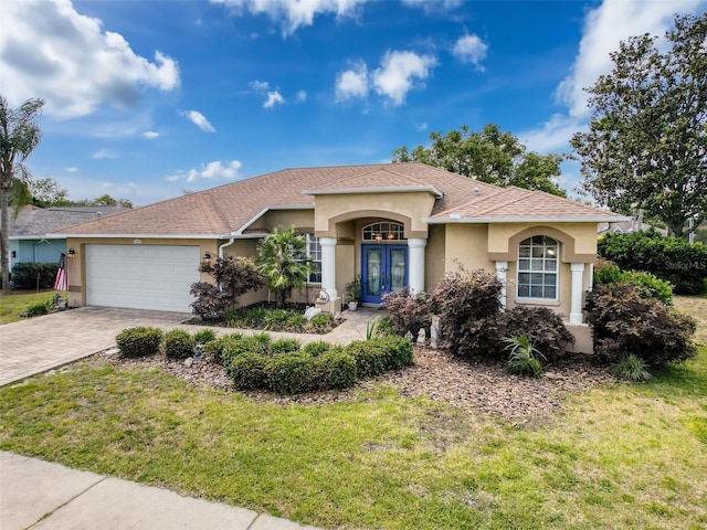 view of front facade featuring stucco siding, a garage, driveway, roof with shingles, and a front lawn