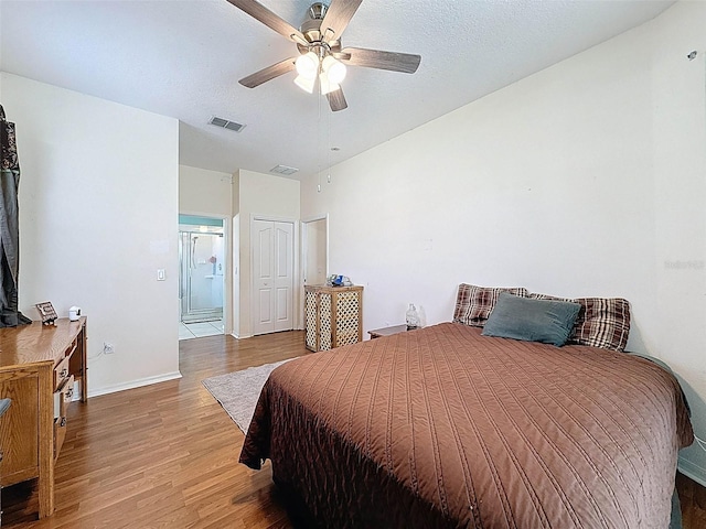 bedroom with baseboards, visible vents, wood finished floors, and a closet