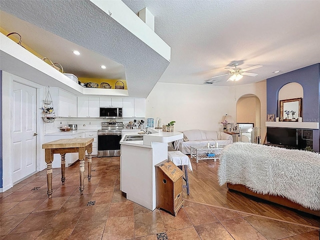 interior space featuring a sink, recessed lighting, a textured ceiling, and arched walkways