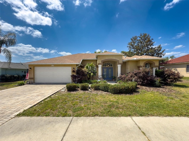 view of front facade with an attached garage, driveway, stucco siding, and french doors